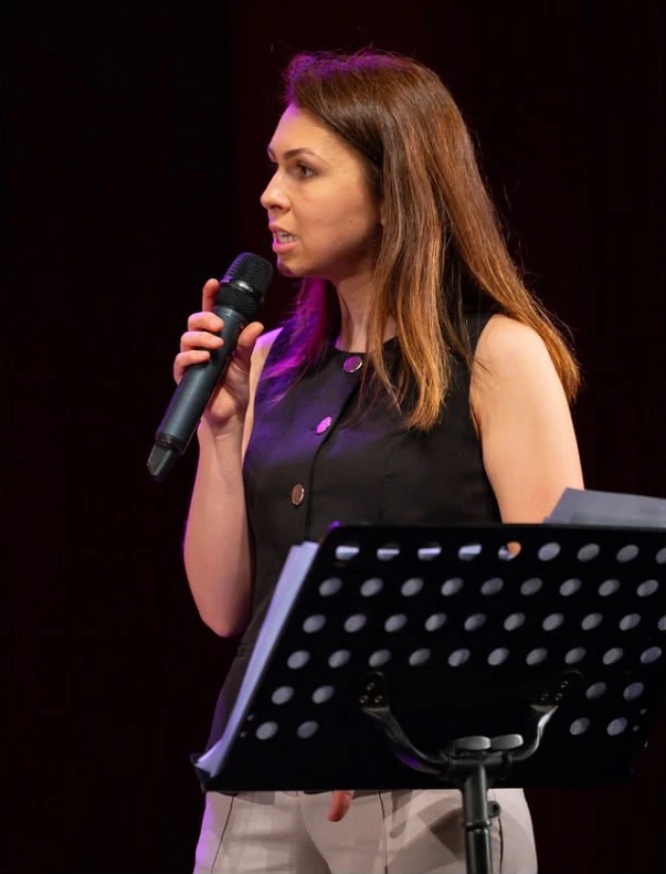 Aura, profesoara de canto D’Aria Music, cu microfonul, pe scenă